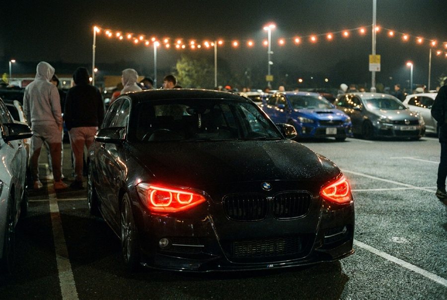 Leon's BMW at a car meet with red DRLs